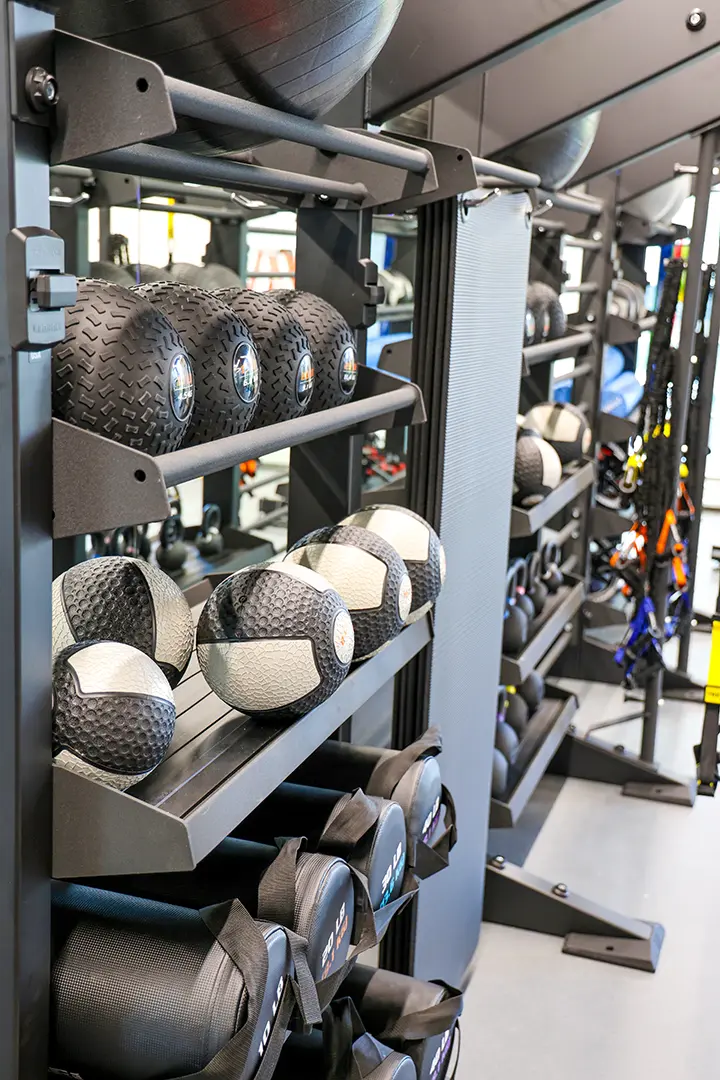 A rack of weights and medicine balls and other exercise equipment